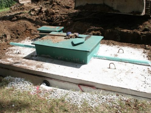 Green septic tank lids and risers installed at ground level over a concrete septic tank, making the access points easy to find