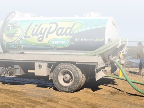 LilyPad Septic pump truck and technician running a hose during a septic tank pumping job in central Kansas